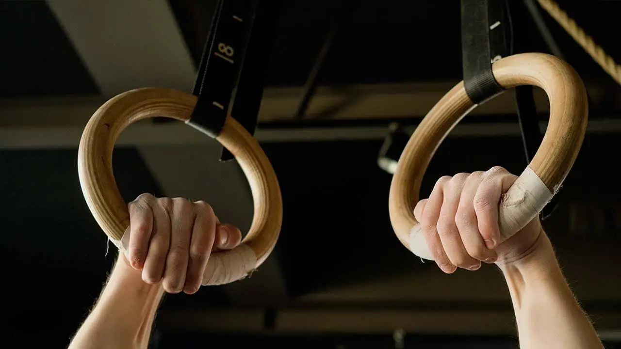 a gymnast using liquid chalk while on gymnastics rings